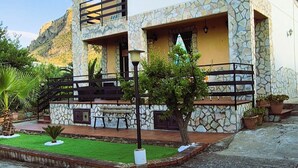 A two-story building with a stone facade, balconies, and a small garden area. - Detached Property with garden and a view on the Sea near Palermo, Sicily (Altavilla Milicia, Torre Colonna-Sperone)