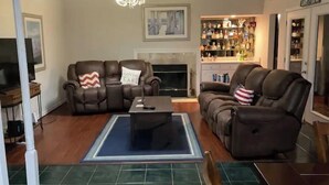 A living room with two leather sofas, a coffee table, a fireplace, and a bar area with liquor bottles.