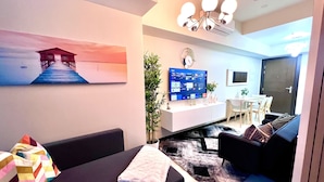Ein modernes Wohnzimmer mit einer Couch, einem Couchtisch, einem Fernseher und einem Essbereich im Hintergrund.