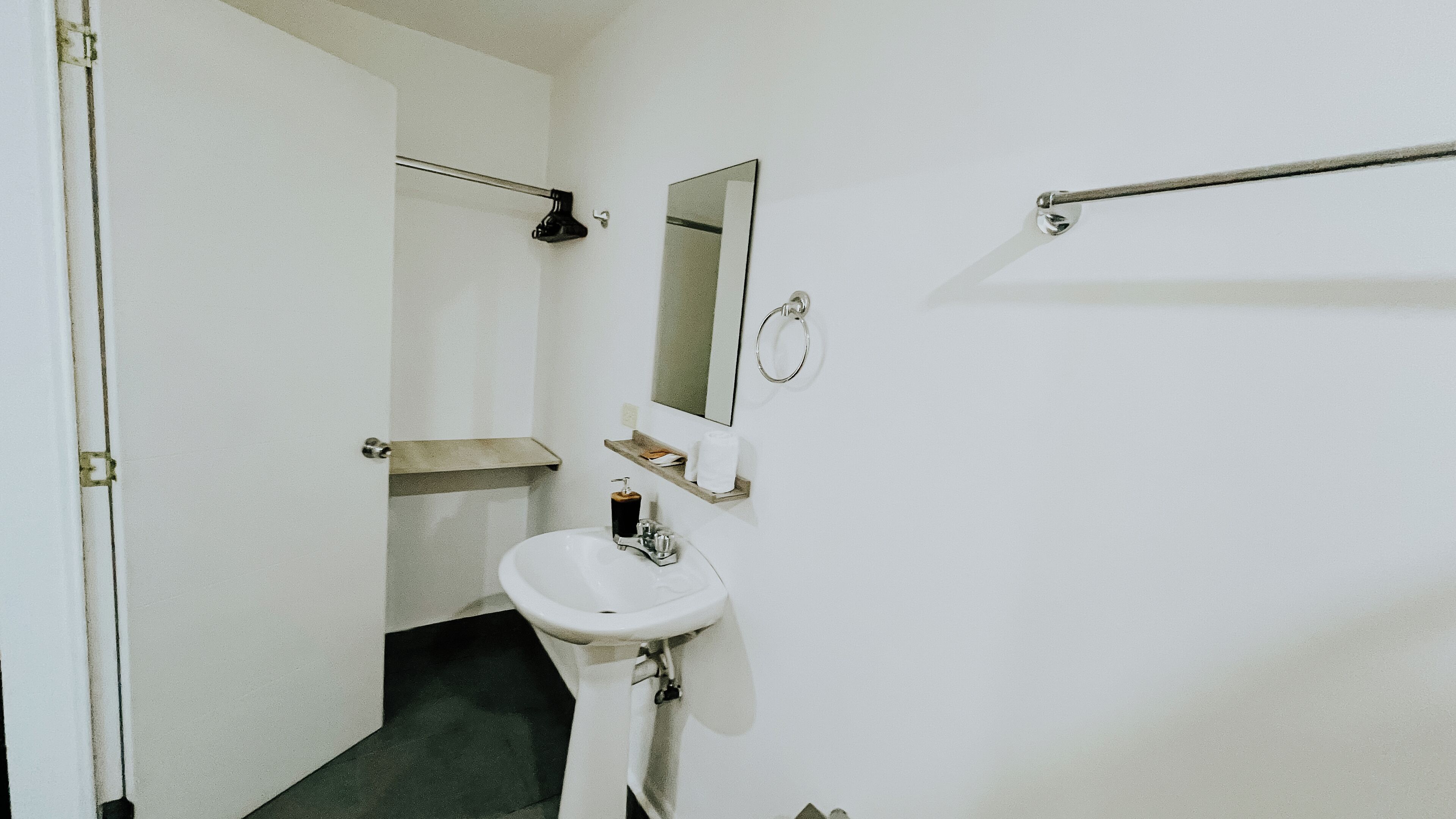 A small, compact bathroom with a white sink, a mirror, a towel rack, and a toilet.