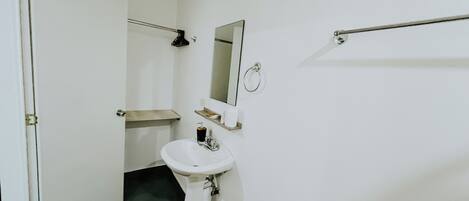 A small, compact bathroom with a white sink, a mirror, a towel rack, and a toilet.