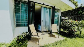 A room with a bed, a chair, and a sliding glass door leading to a balcony. - La Ruta Hotel Corporativo (San Salvador)