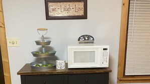 Een keukentafel met een koffiezetapparaat, een weegschaal en een lijst met de tekst 'Leef ~ Lach ~ Geniet'.