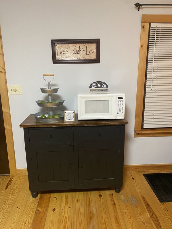 A kitchen counter with a coffee maker, a framed sign, and a fruit bowl. - Cabin in Country close to Lake w Hot Tub. (Tullahoma)