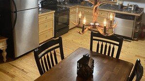 Een keuken met houten kastjes, een roestvrijstalen koelkast, een zwarte kookplaat en een kroonluchter met kaarsen.