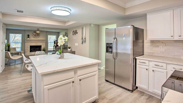 A modern kitchen with white cabinetry, a stainless steel refrigerator, and a marble island. - Richardson Home w/ Pool, Hot Tub & Arcade Games (Richardson)
