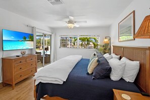 A bedroom with a bed, a TV, a ceiling fan, and a window with a view of palm trees. - " BRING YOUR BOAT!!! Enjoy easy access NEW dock, Pool & more! (Naples)