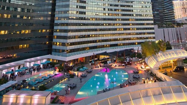 Un hotel modern amb una zona de piscina al terrat, diverses opcions de restaurants i una gran façana de vidre.