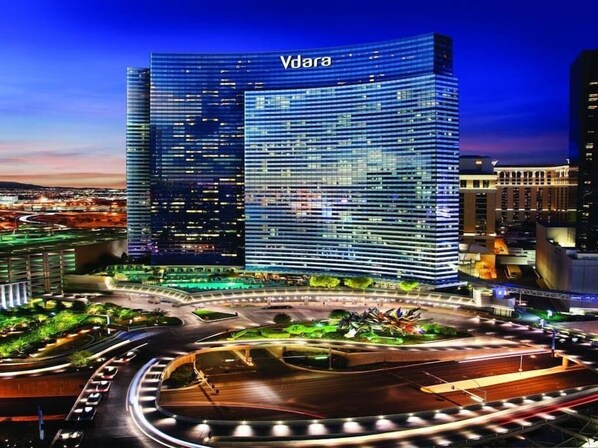 A modern Vdara hotel with a glass facade, surrounded by a landscaped area with a roundabout. - Vdara Studio Suite 011 * Pool View*Free Valet (Las Vegas)