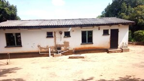A single-story building with a corrugated metal roof, a small porch, and a dirt ground. - Backpacker's rest stop -10 min from downtown & a hike to the Falls!! (Livingstone)