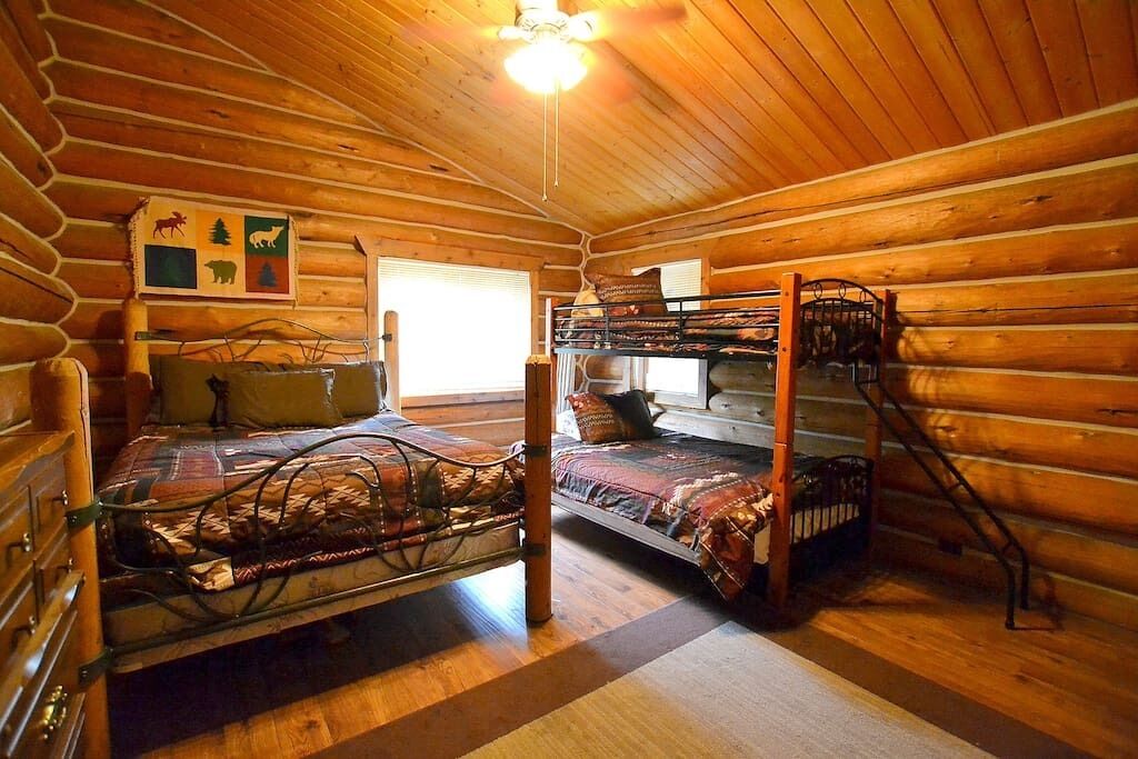 Une cabane avec un lit superposé, un plafond en bois et un tableau représentant des animaux accroché au mur.