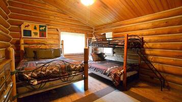Une cabane avec un lit superposé, un plafond en bois et un tableau représentant des animaux accroché au mur.