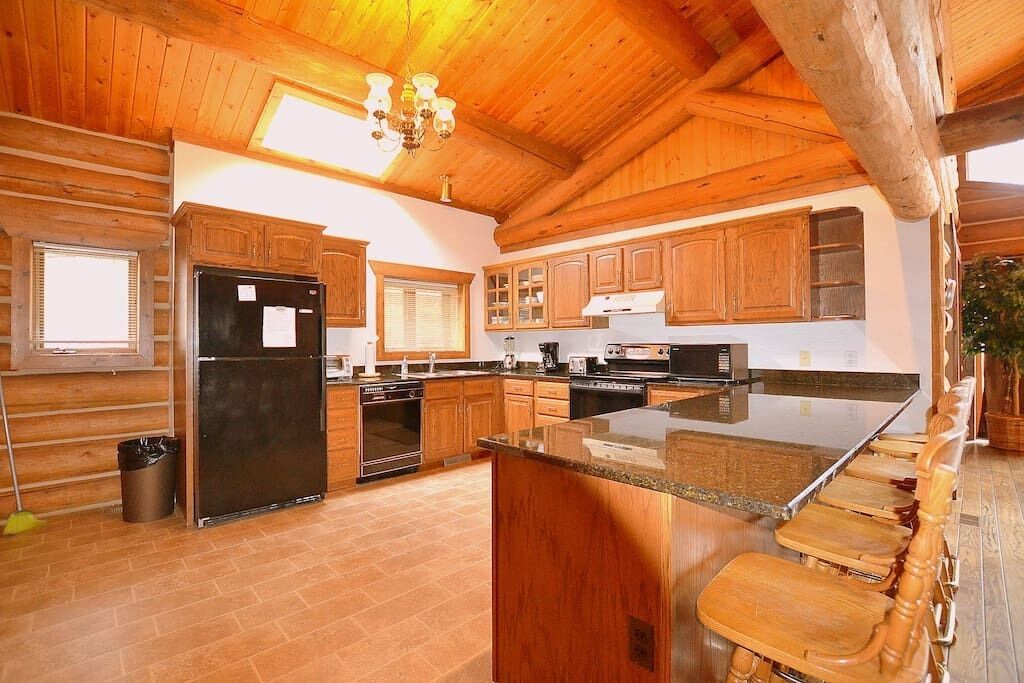 Une cuisine spacieuse avec des meubles en bois, un grand îlot central et un four encastré.