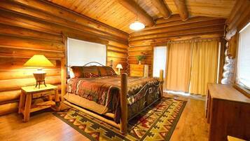 Une chambre à coucher située dans un chalet en rondins, avec un lit en bois, une table de chevet, une lampe et une fenêtre avec des rideaux.