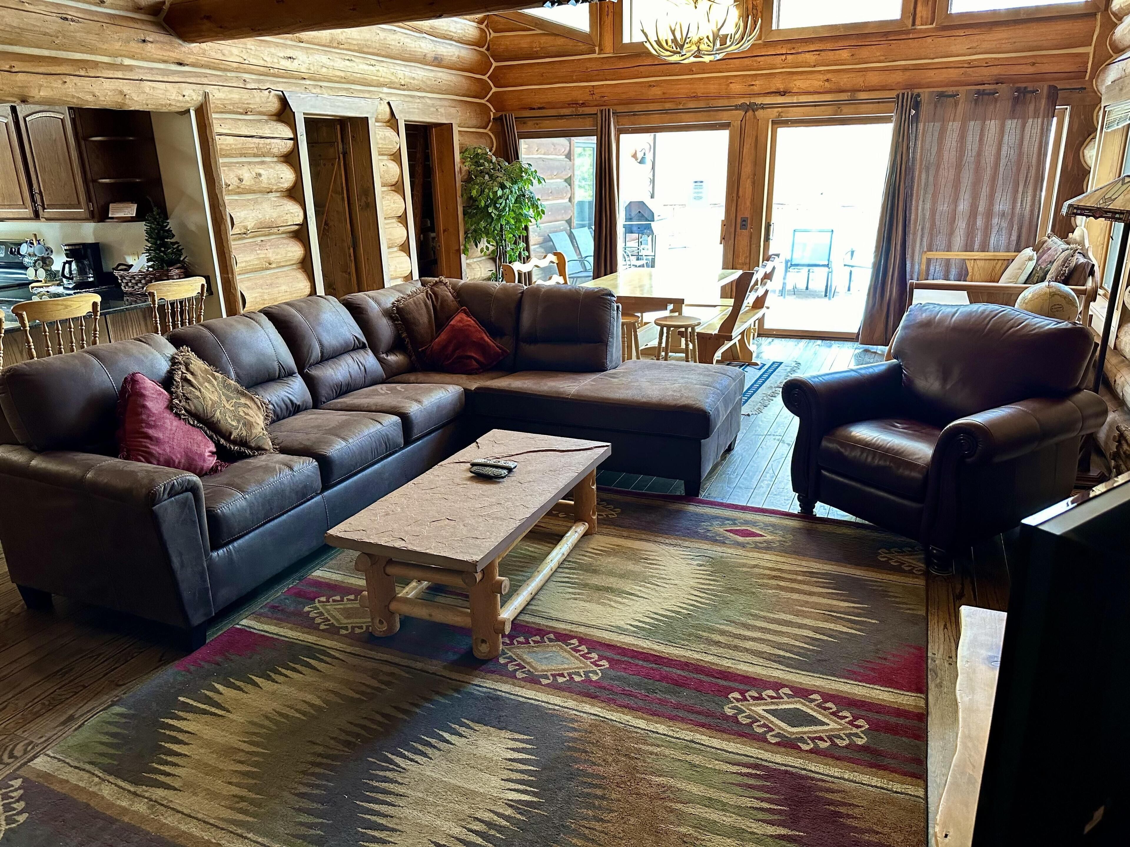 Un intérieur chaleureux de chalet en bois, avec un canapé d’angle, une table basse en bois et un tapis à motifs.