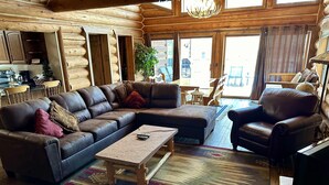 A cozy log cabin interior with a sectional sofa, a wooden coffee table, and a patterned rug.