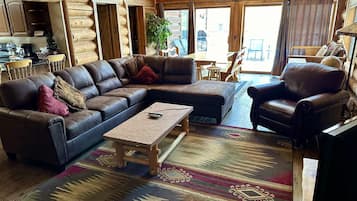 Un intérieur chaleureux de chalet en bois, avec un canapé d’angle, une table basse en bois et un tapis à motifs.