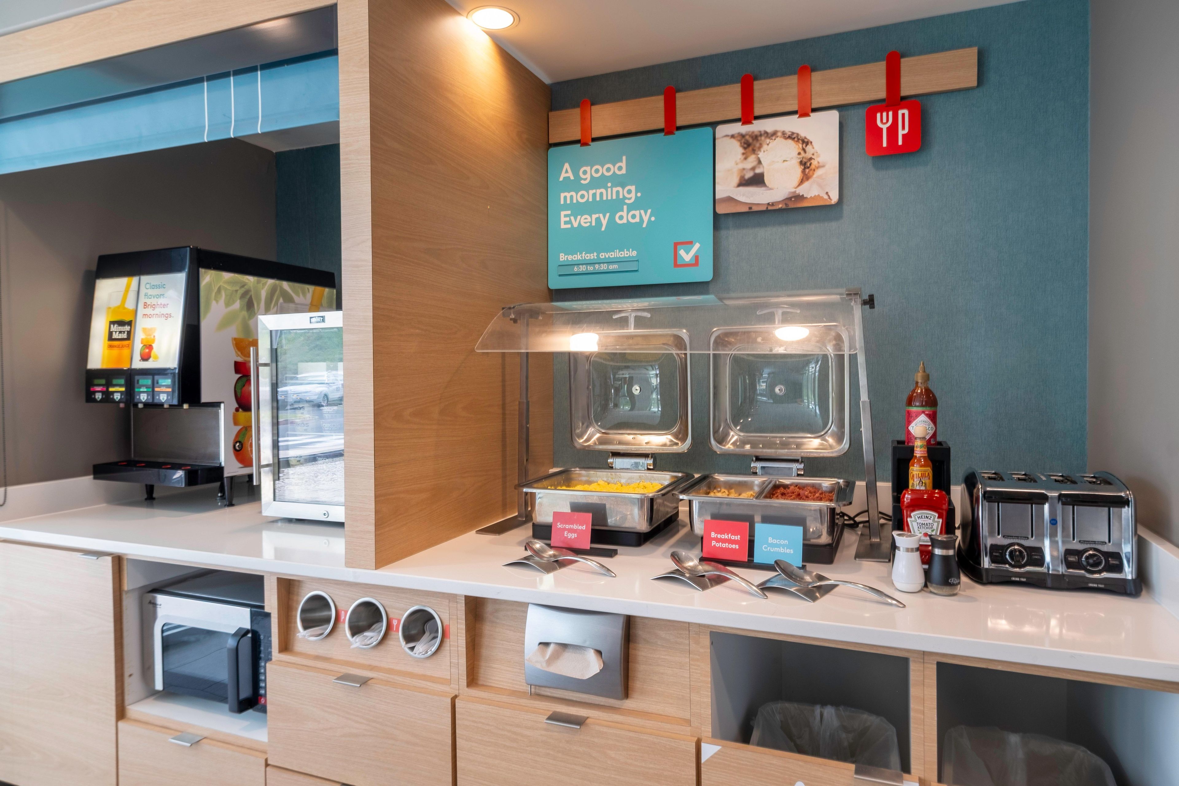 Estación de desayuno con recipientes etiquetados para huevos revueltos, cereal y tostadas.