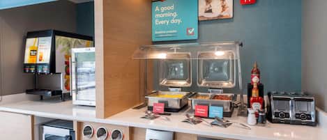 Un buffet pour le petit-déjeuner avec des récipients étiquetés pour les œufs brouillés, les céréales et les toasts.