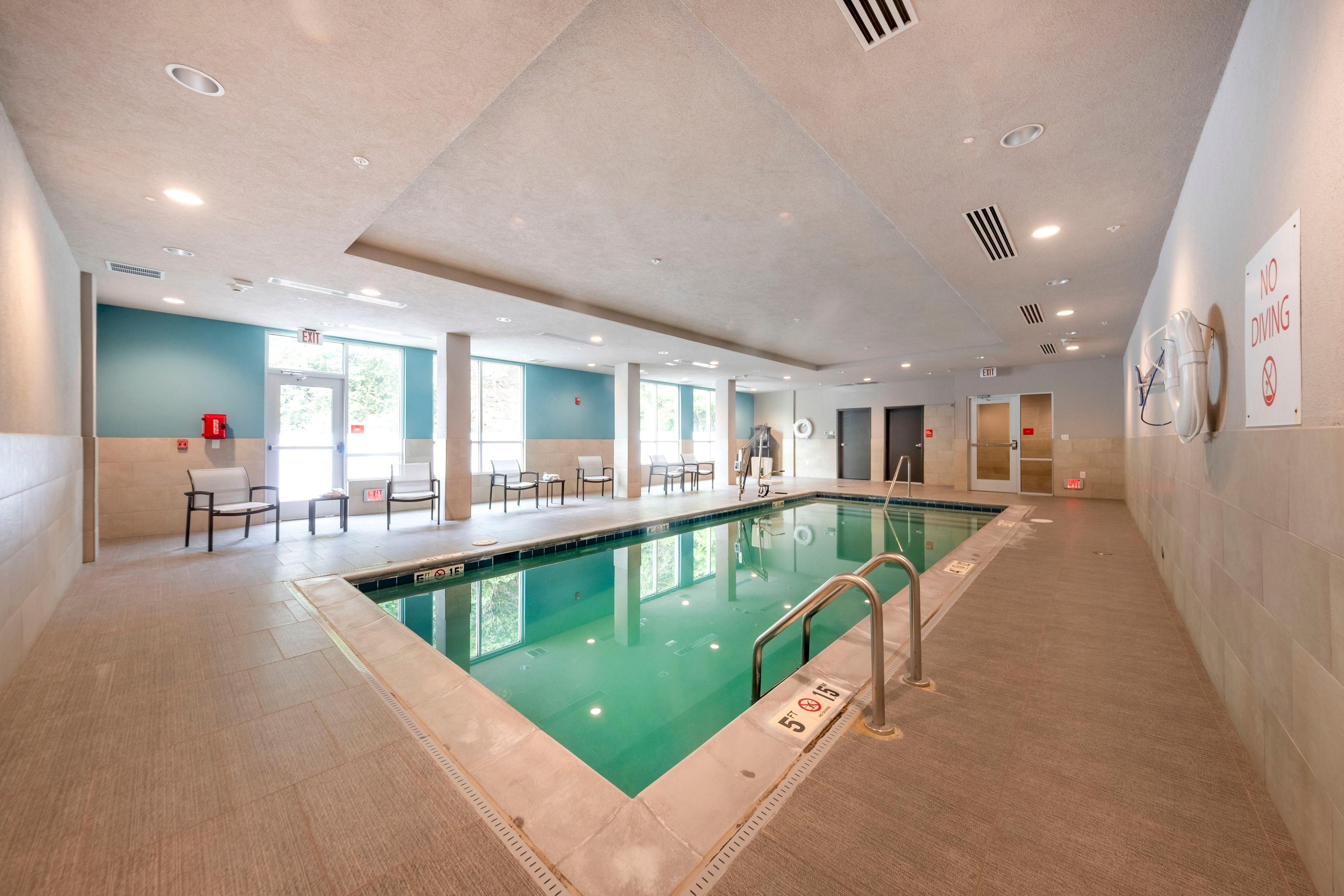Piscina con señal de prohibido bucear, zona de estar interior y señales de salida.