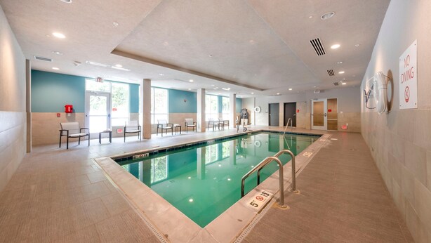 Piscina con señal de prohibido bucear, zona de estar interior y señales de salida.