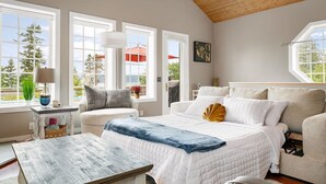 A bedroom with a large bed, a wooden ceiling, and multiple windows. - Ocean Bliss — Coastal Retreat on Skagit Bay (La Conner)