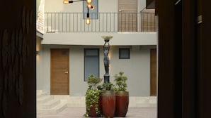 Ein Korridor mit einem modernen Gebäude im Hintergrund, einer Holztür und einem Blumentopf.