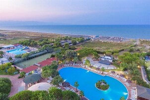 Un resort con una amplia piscina, zona de playa y varios edificios.