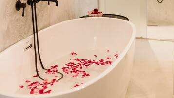 A modern bathroom with a freestanding bathtub, a shower, and a towel rack.