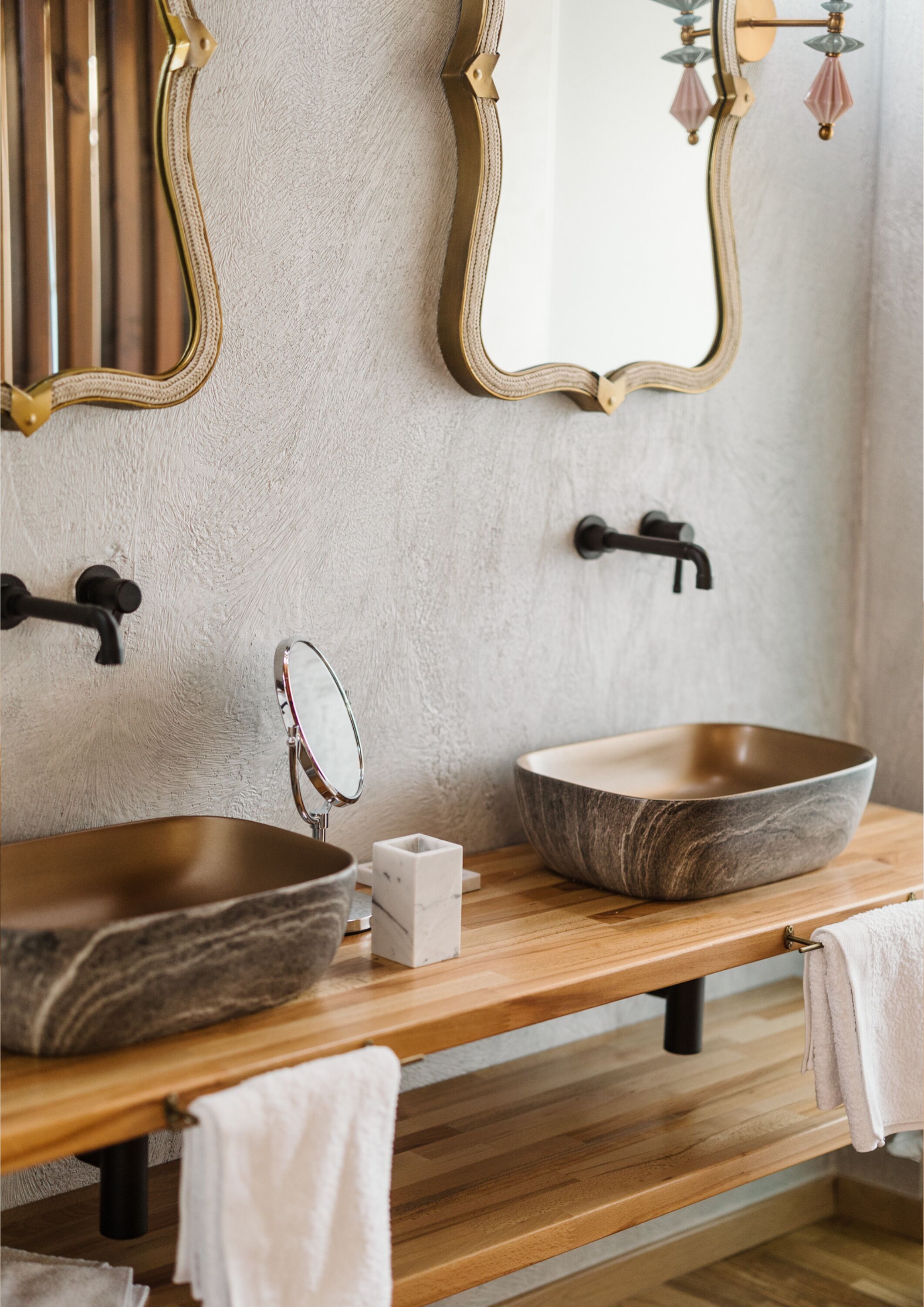 A bathroom with two sinks, each with a mirror and a towel. There is a wooden countertop and a towel rack.