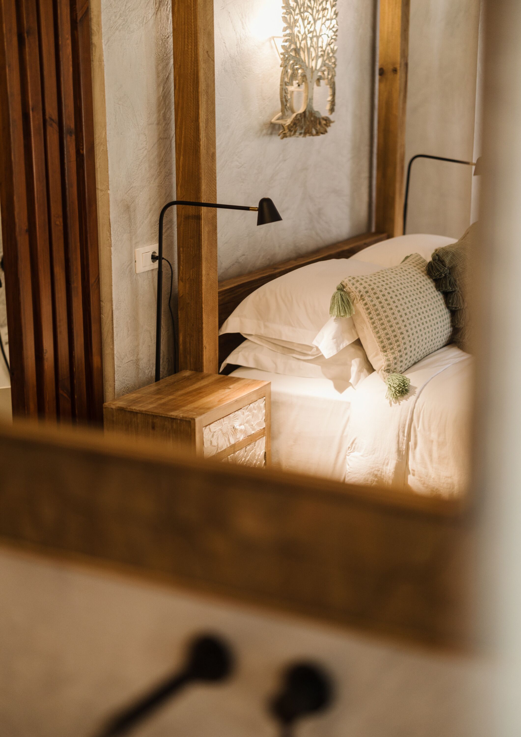A bedroom with a wooden headboard, a bedside lamp, a nightstand, and a bed with white bedding.