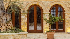 A building with a stone facade, multiple arched doorways, and a tiled roof. - Blerina's Village Project  (Kamëz)