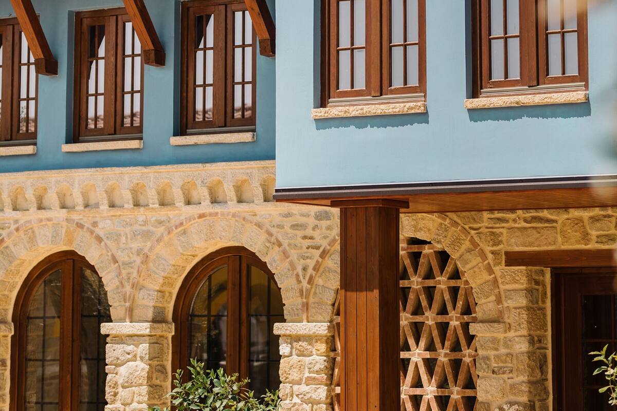 Un edificio con fachada azul, arcos de piedra y marcos de madera para las ventanas.