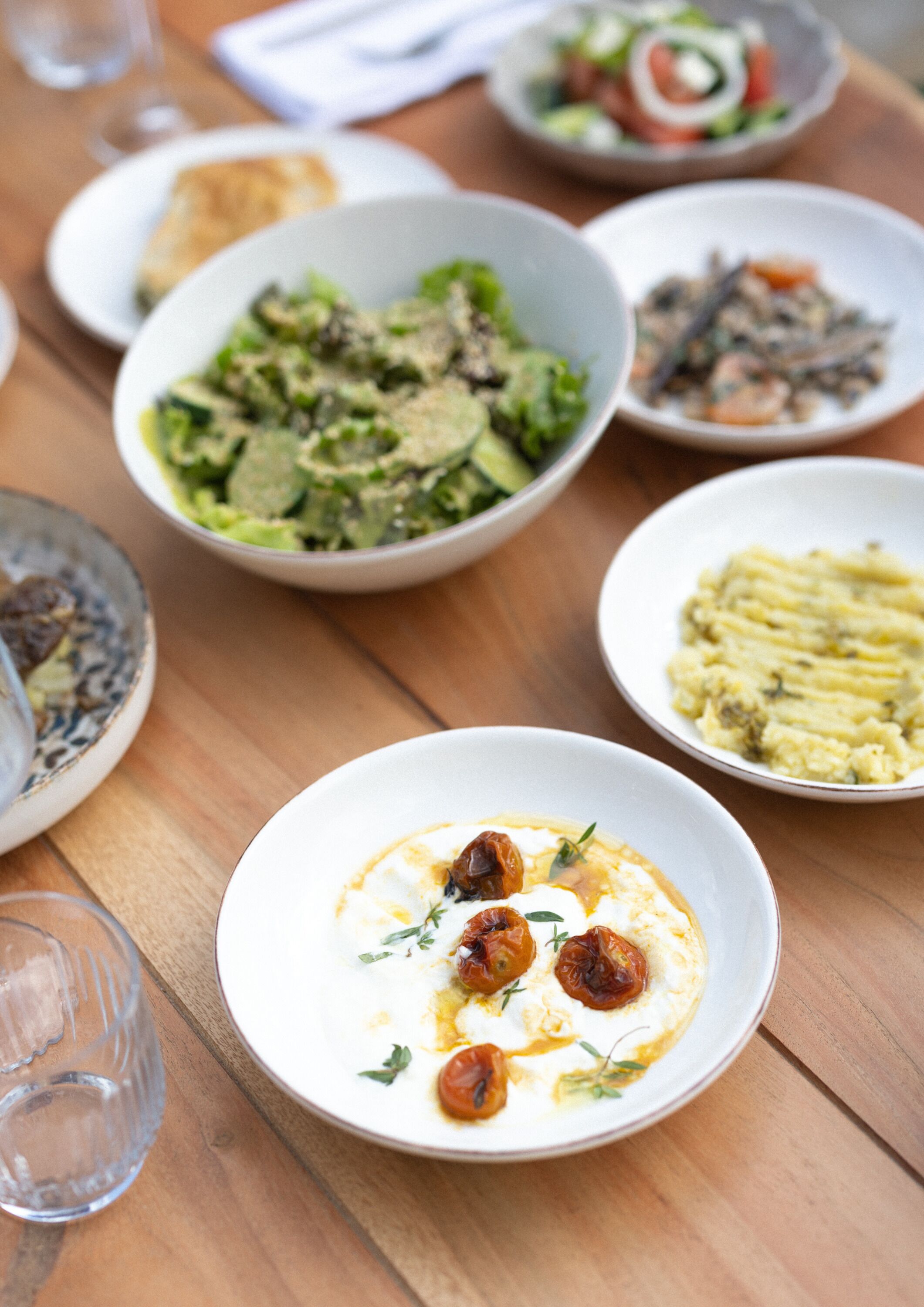 Un tavolo da pranzo con diversi piatti, tra cui un'insalata, una zuppa e purè di patate.