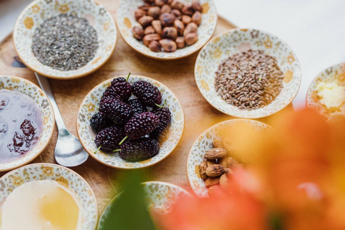 Una mesa con diferentes alimentos en recipientes pequeños, como nueces, semillas y bayas.