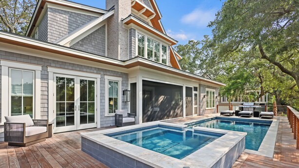 Una casa moderna con una amplia terraza, dos piscinas y un patio cubierto.