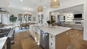 Una cocina moderna con una isla grande, armarios de madera y lavavajillas integrado.