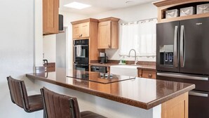 A modern kitchen with a central island, bar stools, built-in appliances, and a large refrigerator.