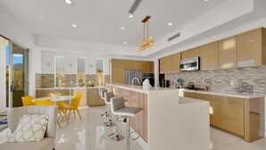 Una cucina moderna con isola centrale, sgabelli da bar e zona pranzo con sedie gialle.