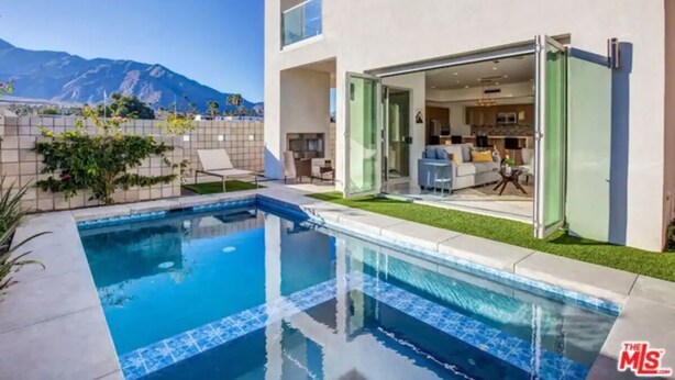 Una casa moderna con piscina, patio e vista sulle montagne.