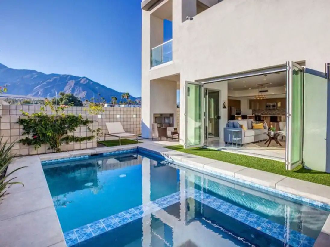 A modern house with a swimming pool, a patio, and a mountain view.