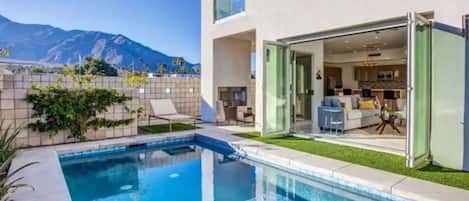 A modern house with a swimming pool, a patio, and a mountain view.