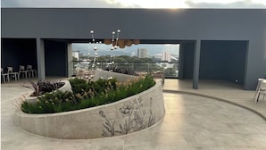 Una terraza en la azotea con un jardín circular, zona de estar y vistas del horizonte de la ciudad.