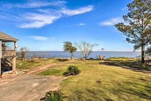 A coastal property with a grassy lawn, a wooden deck, and a view of the sea.