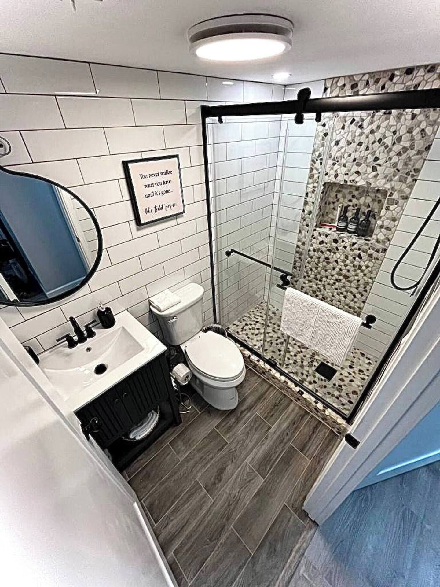 Un baño moderno con cabina de ducha de vidrio, inodoro, lavamanos y espejo.