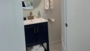 A bathroom with a white sink, dark cabinet, and a towel rack. - Light, bright & clean, studio guest suite with private entrance and hot tub! (Redmond)