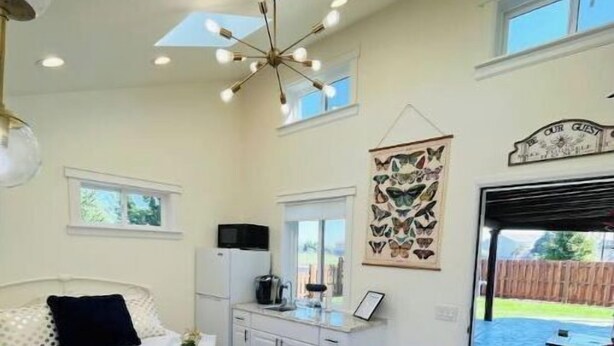 A bedroom with a bed, a desk, a chair, a window, and a door leading to a balcony. - Light, bright & clean, studio guest suite with private entrance and hot tub! (Redmond)