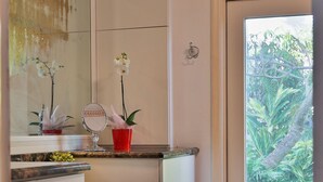 Een badkamer met een spiegel, een rode bloevas en een potorkidee.