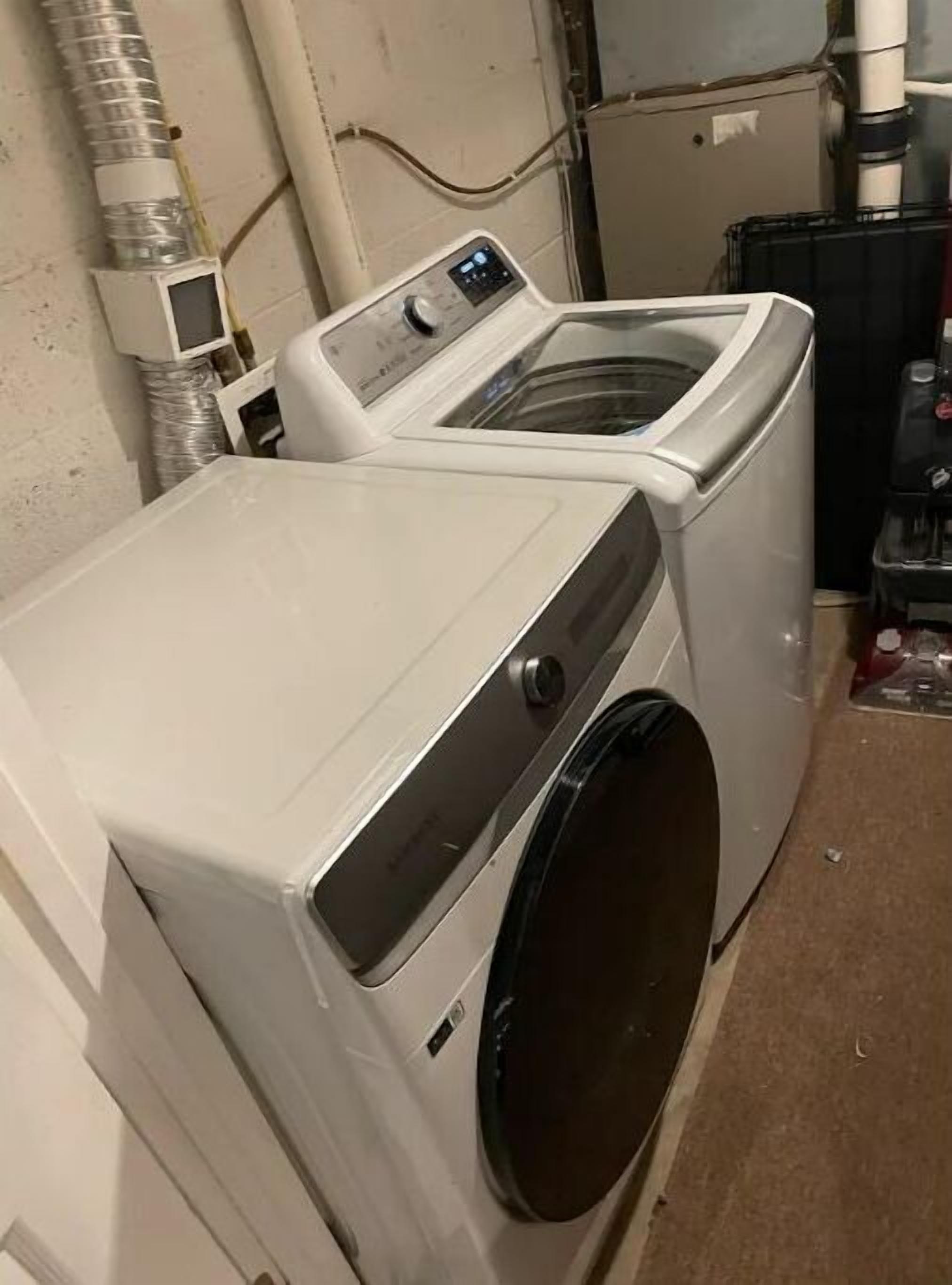 Une machine à laver et un sèche-linge à chargement frontal, placés l’un sur l’autre dans une buanderie.