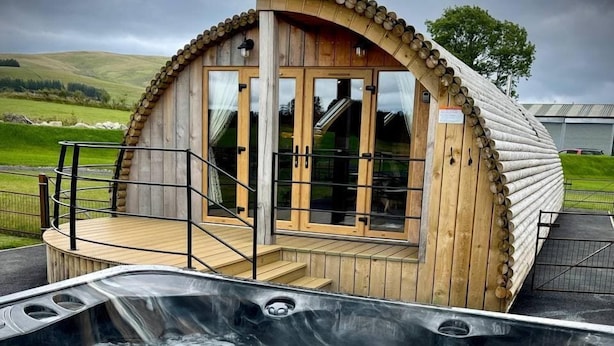 A wooden cabin with a hot tub in front.